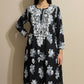 Black dress with white floral pattern on a mannequin against a beige background