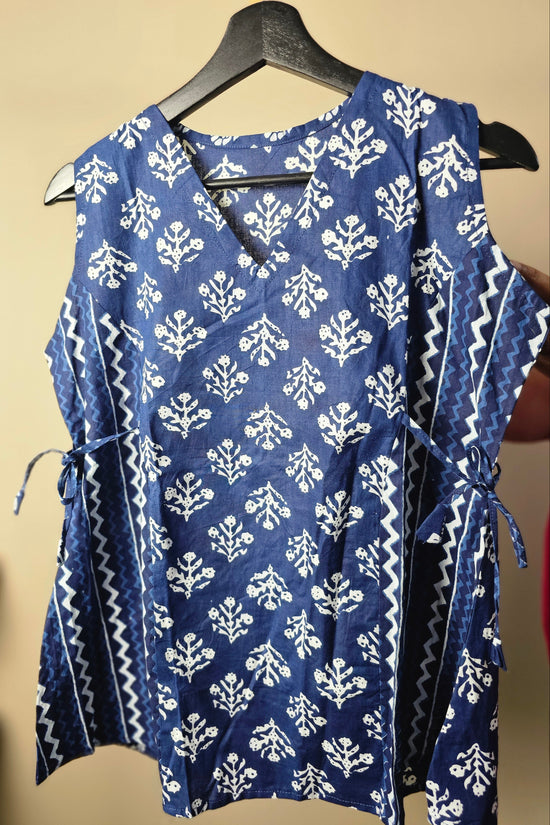 Blue and white patterned dress on a hanger against a beige background