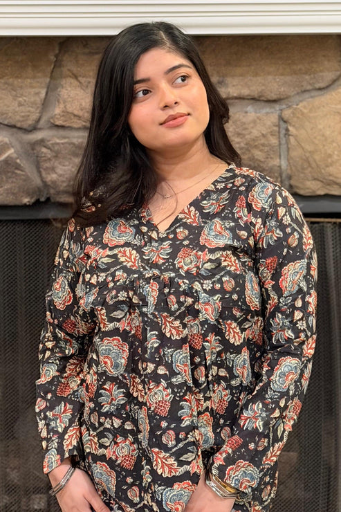 Woman standing in front of a stone fireplace with decorative items.