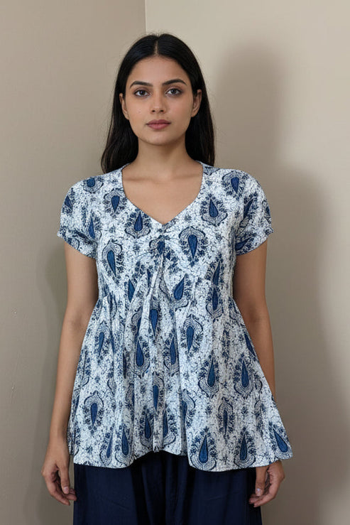 White blouse with blue patterns on a mannequin against a beige background
