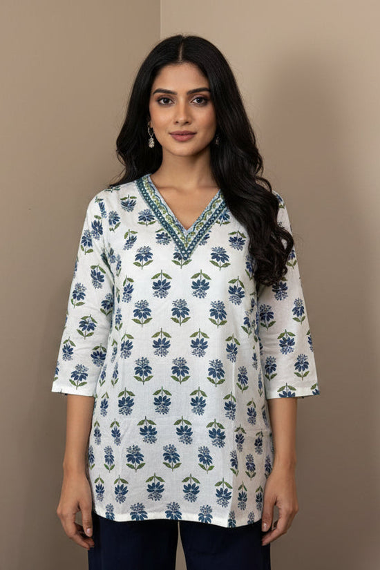 White blouse with blue floral pattern on a mannequin against a brown background