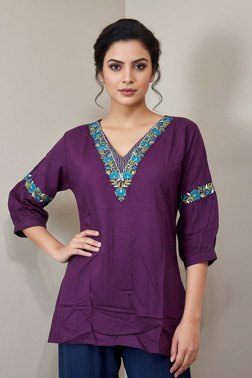 Purple top with colorful embroidery on a mannequin against a beige background