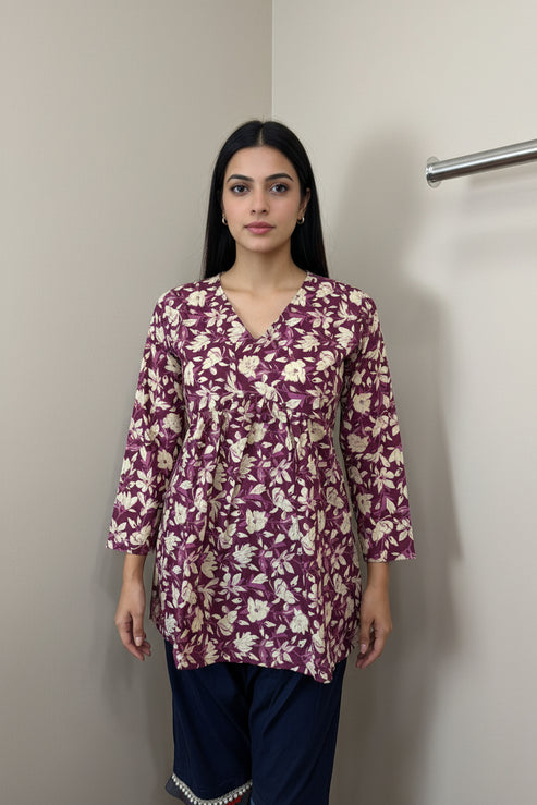 Mannequin wearing a purple floral long-sleeve top against a neutral background