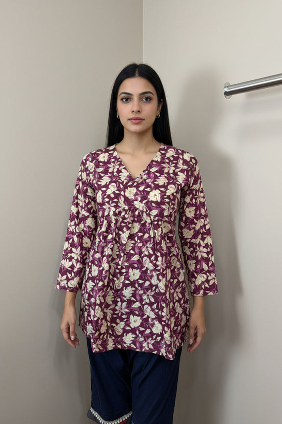 Mannequin wearing a purple floral long-sleeve top against a neutral background