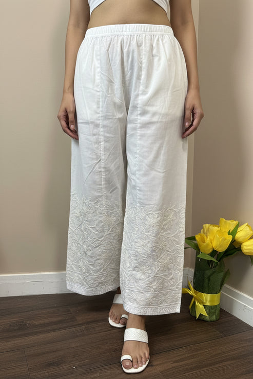 White textured fabric on a stand with a vase of yellow flowers in the background.