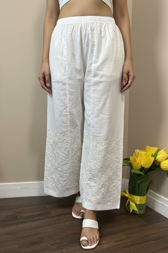 White textured fabric on a stand with a vase of yellow flowers in the background.