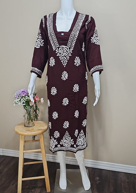 Mannequin wearing a maroon dress with white patterns in a room setting.