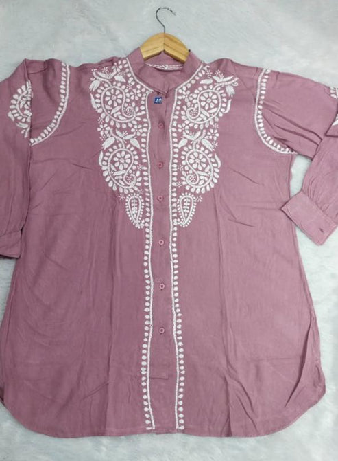 Pink shirt with white lace details on a hanger against a light gray background