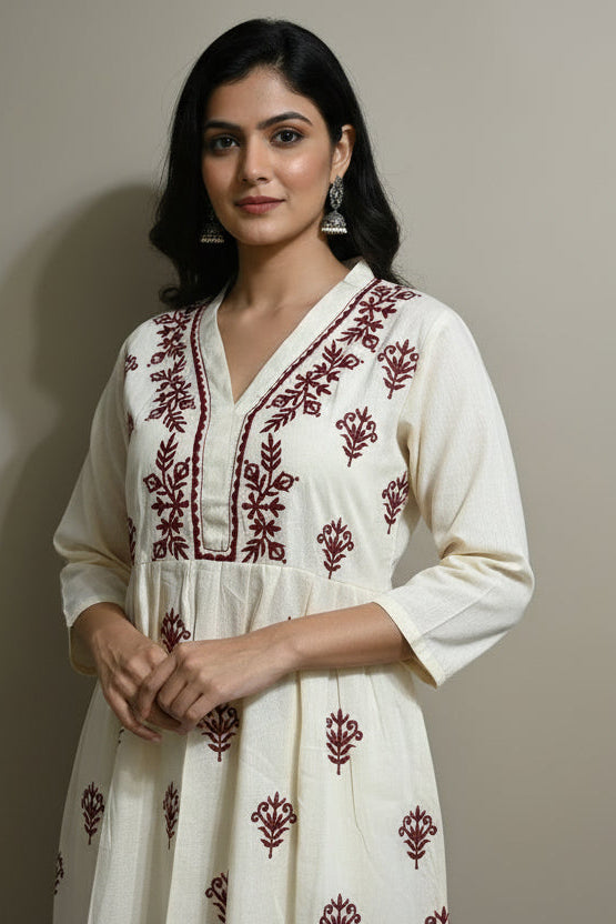 Beige dress with red embroidery on a mannequin against a plain background