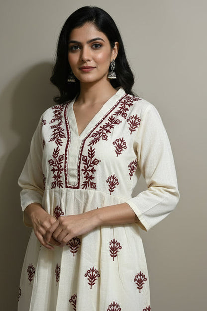 Beige dress with red embroidery on a mannequin against a plain background
