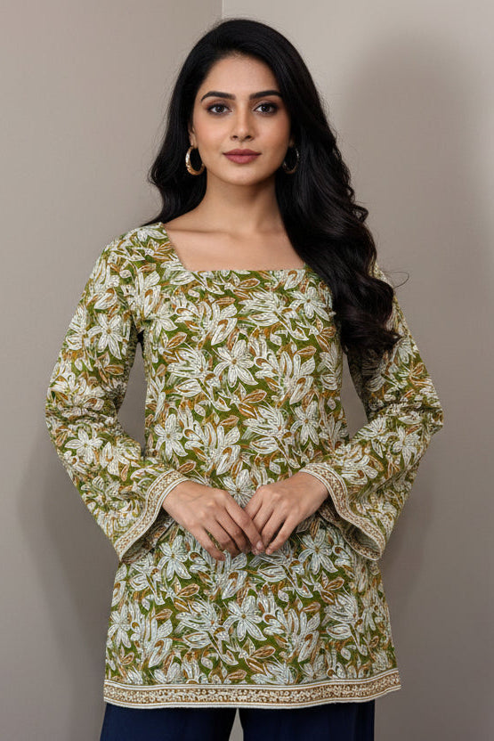 Green floral blouse with navy pants on a mannequin against a gray background