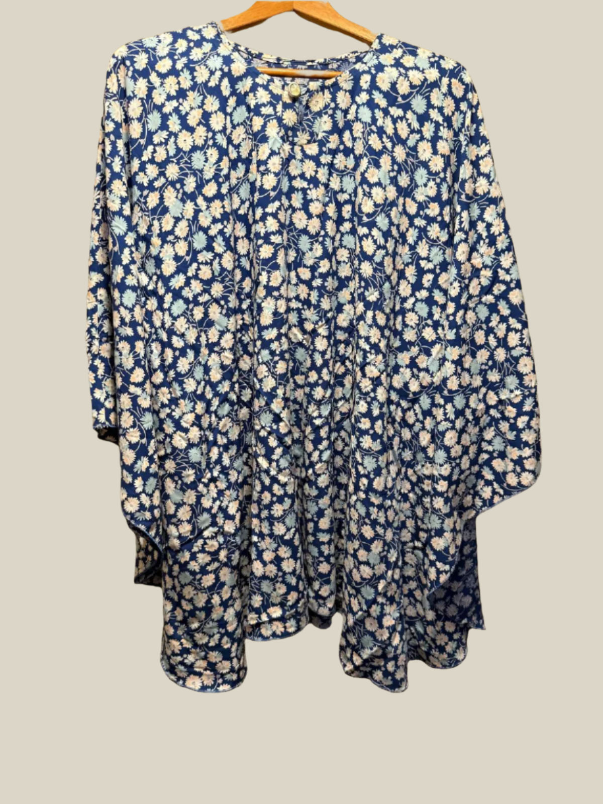 Blue floral dress on a hanger against a plain background